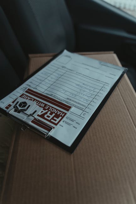 A close-up view of a floral gift being prepared for same day flower delivery by [COMPANY_NAME] as displayed on a black clipboard with a 'FRAGILE HANDLE WITH CARE' notice, resting atop a cardboard box.
